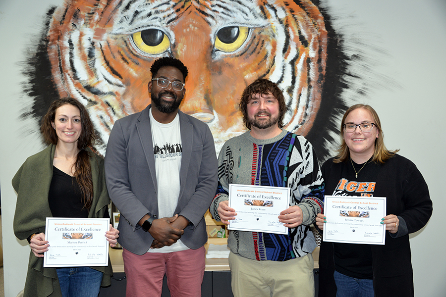students recognized standing in front of a tiger mural on the wall holding certificates