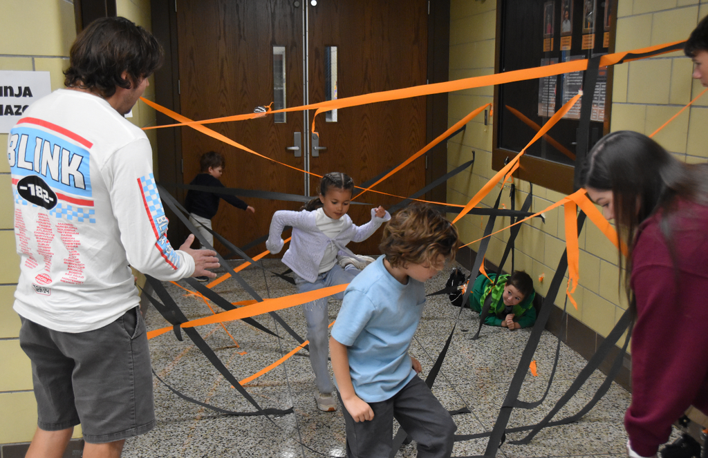 Students are having fun while running through orange and black party streamers that are taped to the floor and walls