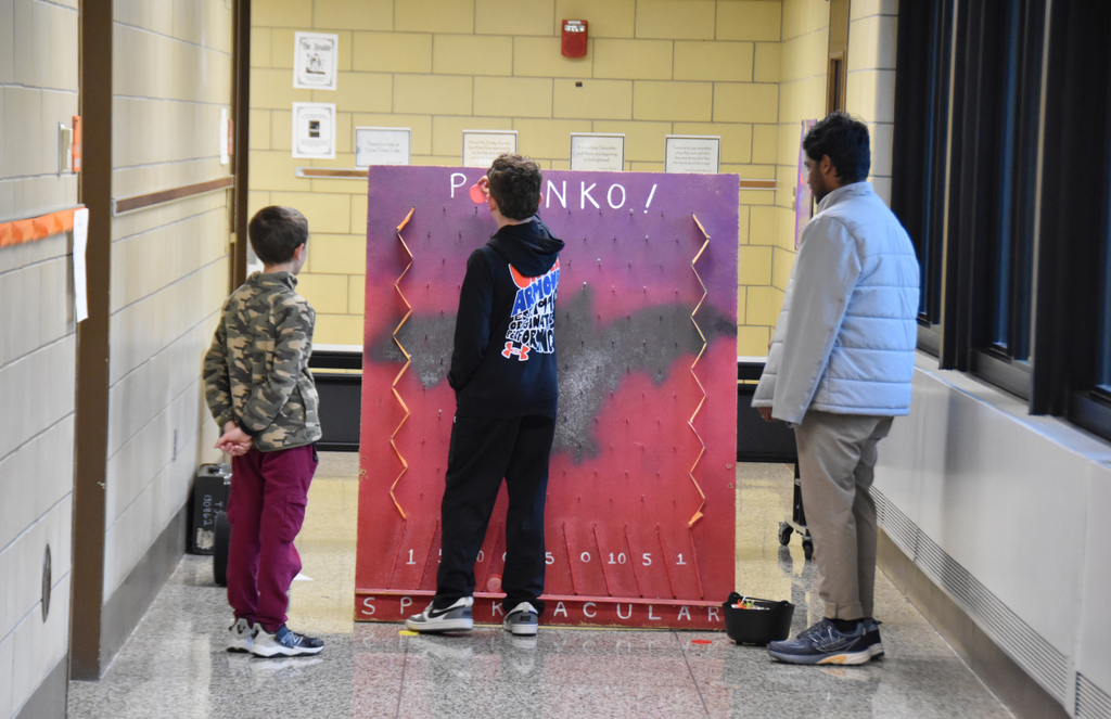 Students playing a plinko-like game in the hallway