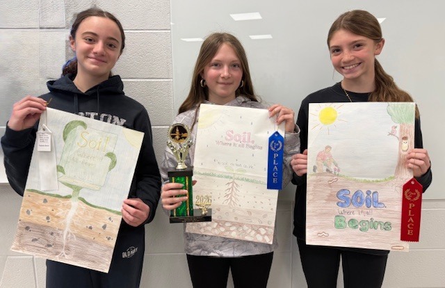 three students pose with their poster and award ribbons