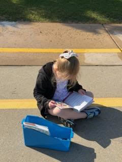 kindergarten student reading outside