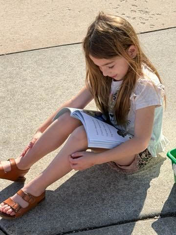 kindergarten student reading outside