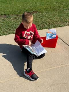kindergarten student reading outside