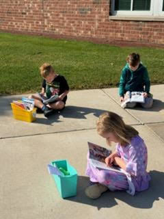 kindergarten student reading outside