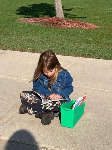 kindergarten student reading outside