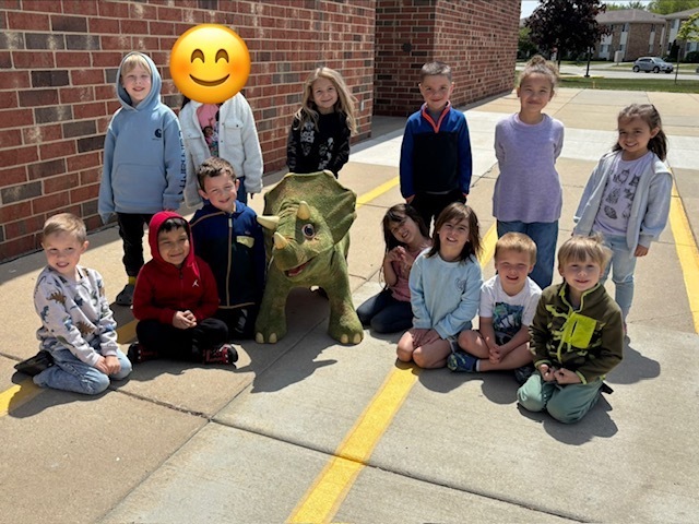 4K students pose for a phone with their ride-on dino friend
