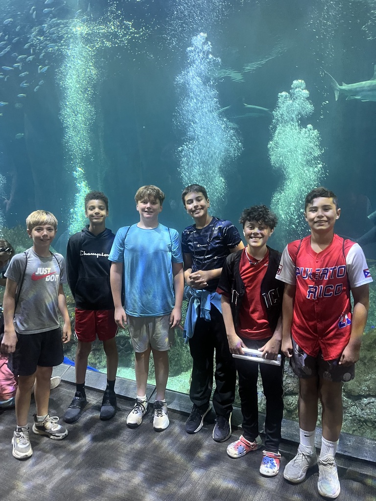 students pose in front of an aquarium tank