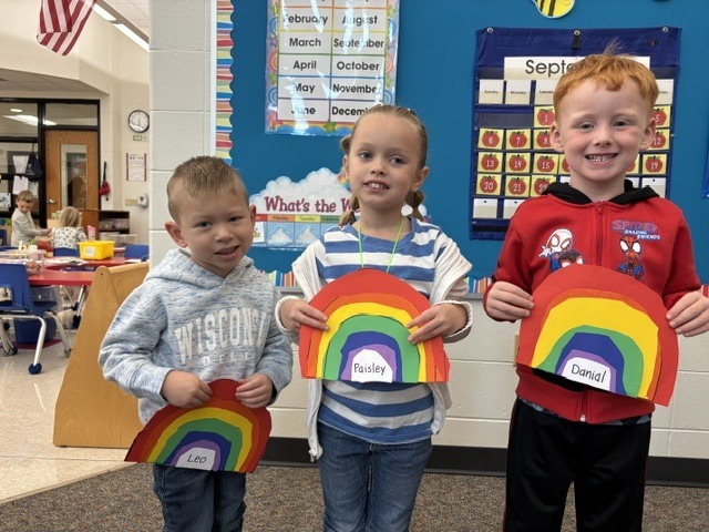 students pose with rainbow art projects