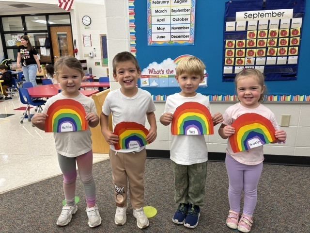 students pose with rainbow art projects