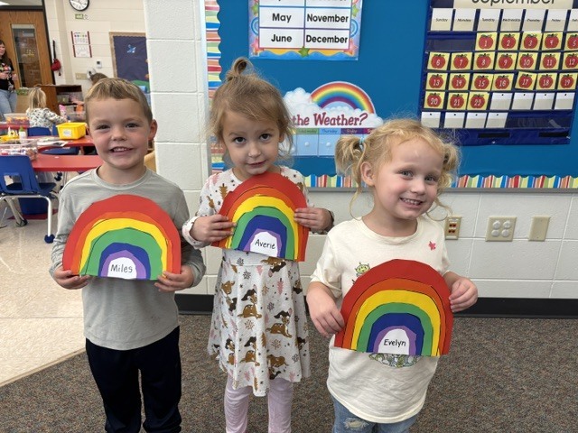 students pose with rainbow art projects