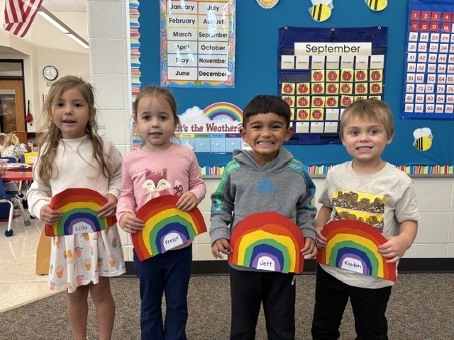 students pose with rainbow art projects