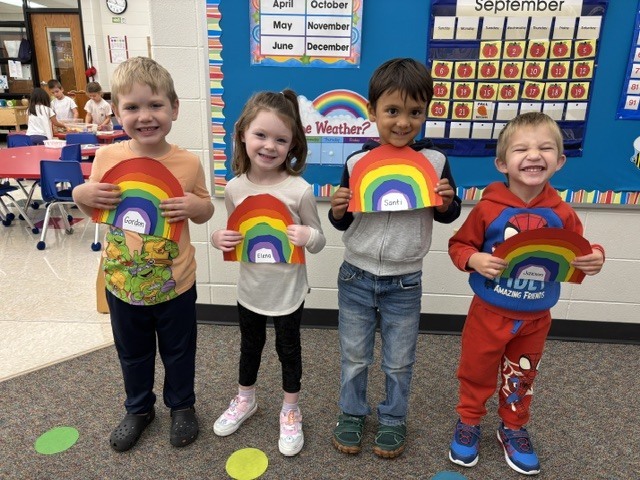 students pose with rainbow art projects