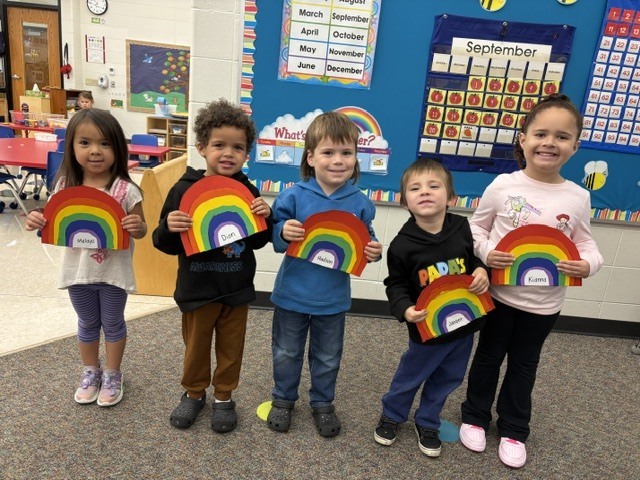 students pose with rainbow art projects