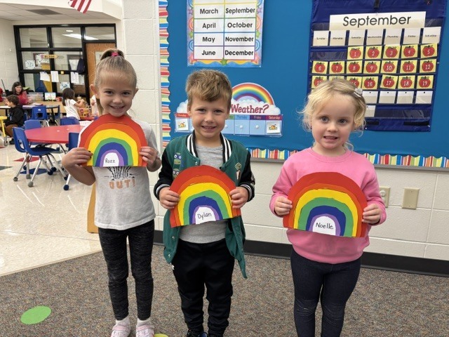 students pose with rainbow art projects