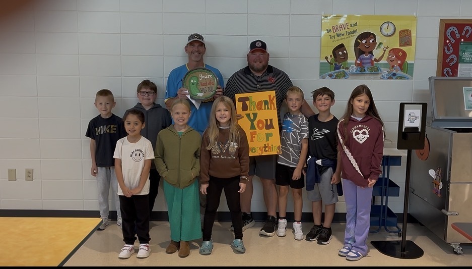 students pose for a photo with two custodians