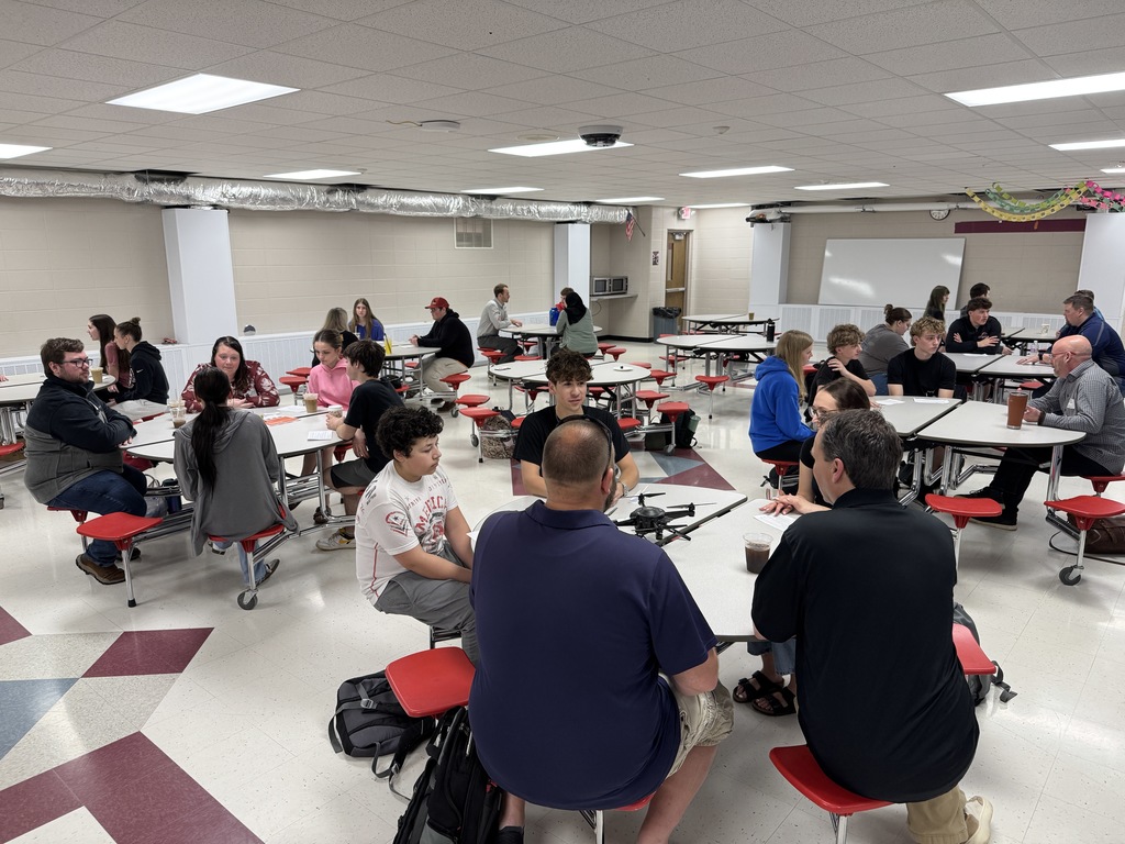 Students and business people sitting and talking at round tables.