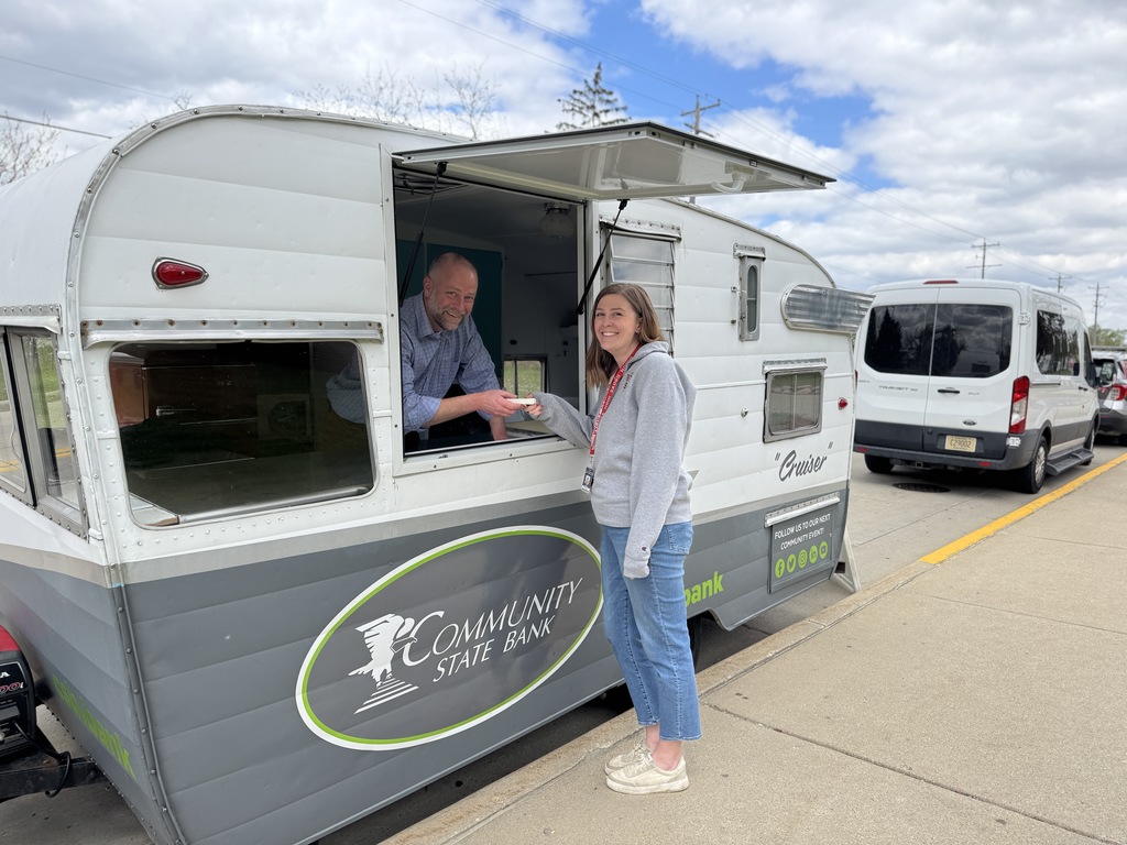 Person inside a camper van with the door open and another person handing them something.