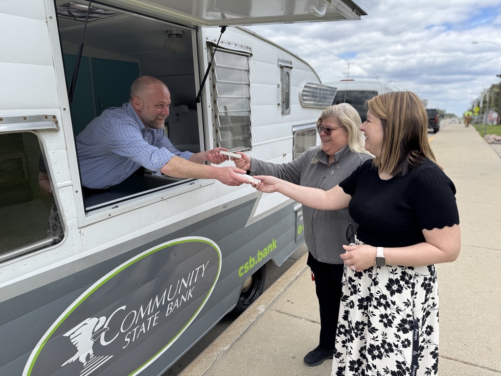 Three people stand by a Community State Bank truck, with a man handing ice cream to a woman.