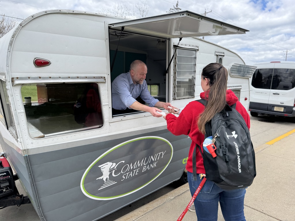 Person with backpack receives food from a man in a window of a food truck.