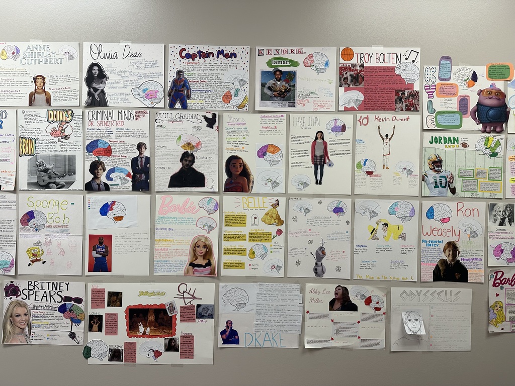 A collection of various designs and images pinned to a wall, including photos of individuals, diagrams, and other visual content.