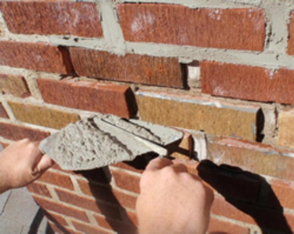person tuck pointing brick