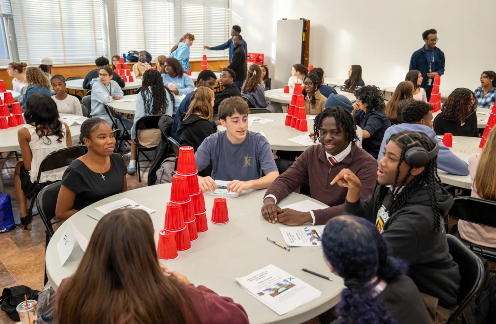 Students from different schools around a table 