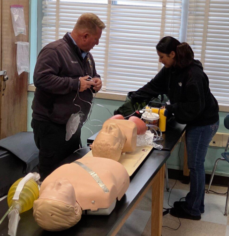Bill Bedula, Uniondale High School lab instructor, with students demonstrating how to save a life – on a medical dummy.