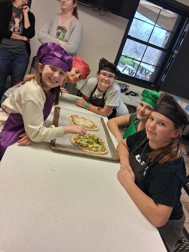 kids putting their final touches on their pizza before it goes in the oven