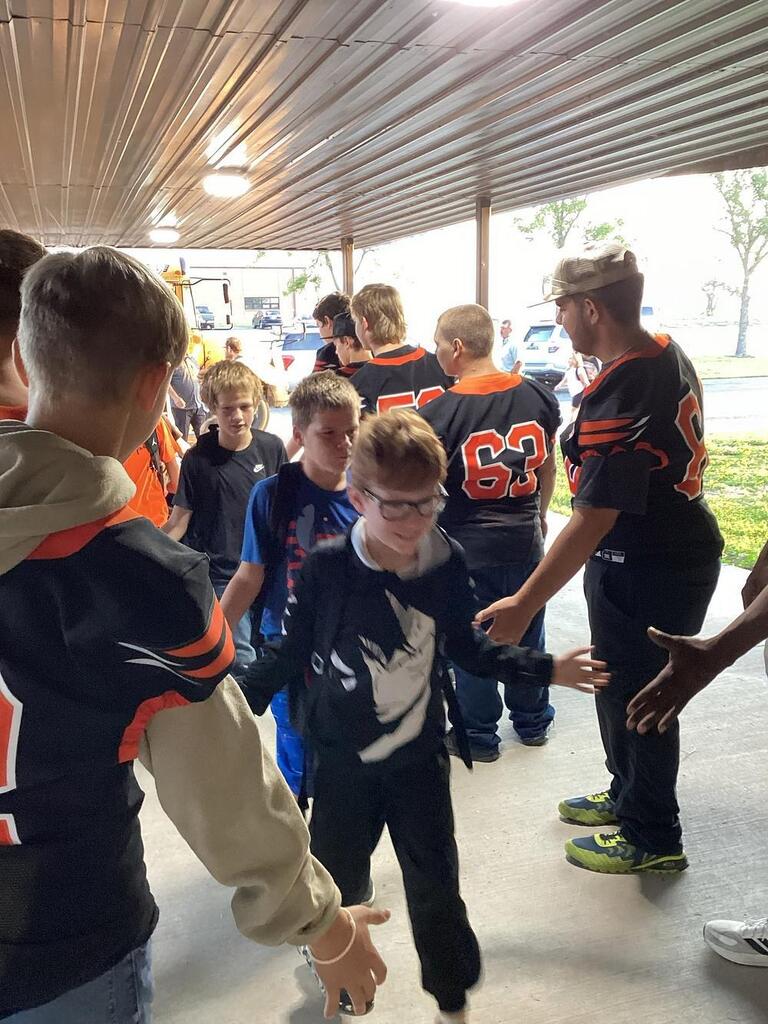 UHS football team giving high fives to WBE students