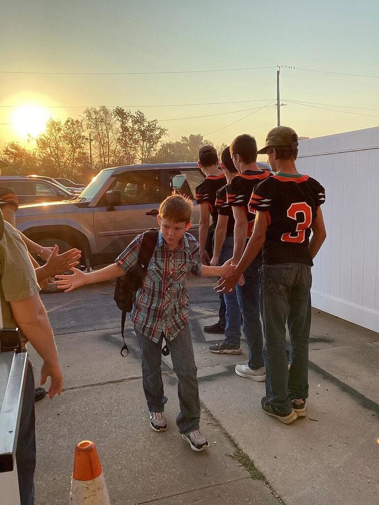 UHS football team giving high fives to WBE students
