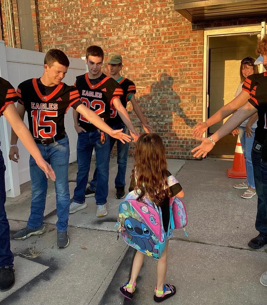 UHS football team giving high fives to WBE students