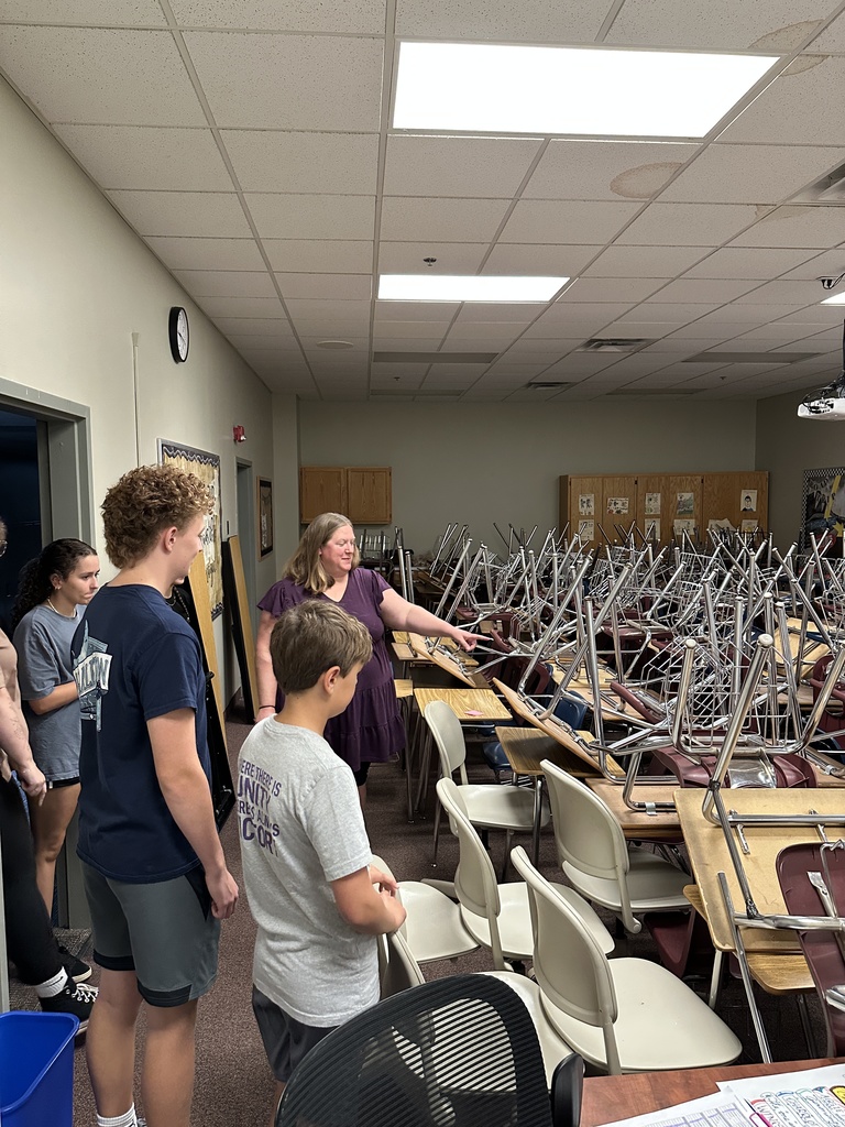 teacher showing student helpers which desks need to be moved where