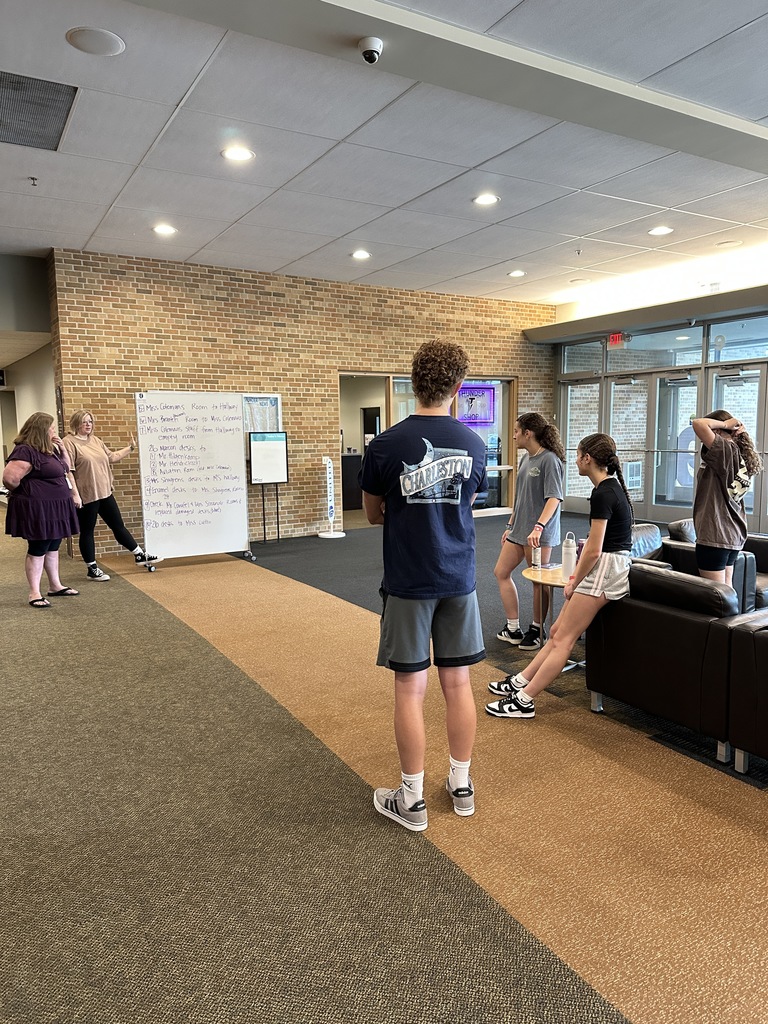 students looking at a whiteboard with the moving plans written on it