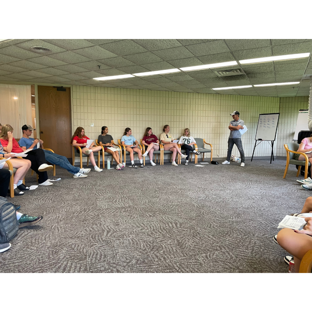 teacher speaking to a group of students at a leadership retreat