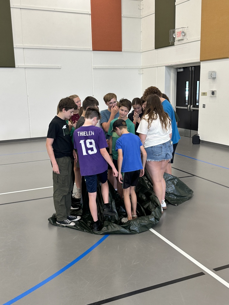 students standing on a tarp working on a team-building exercise