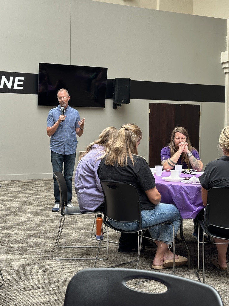 staff sitting at tables while a pastor prays for the meal