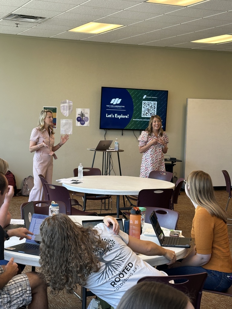 two presenters at the front of a classroom speaking to a group of teachers