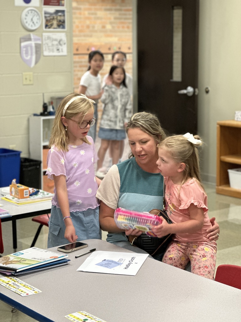 mom and daughters putting school supplies in their classroom