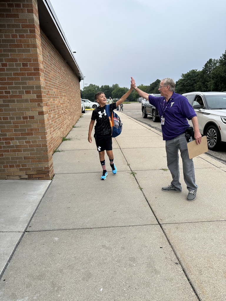 elementary principal welcoming students into the building