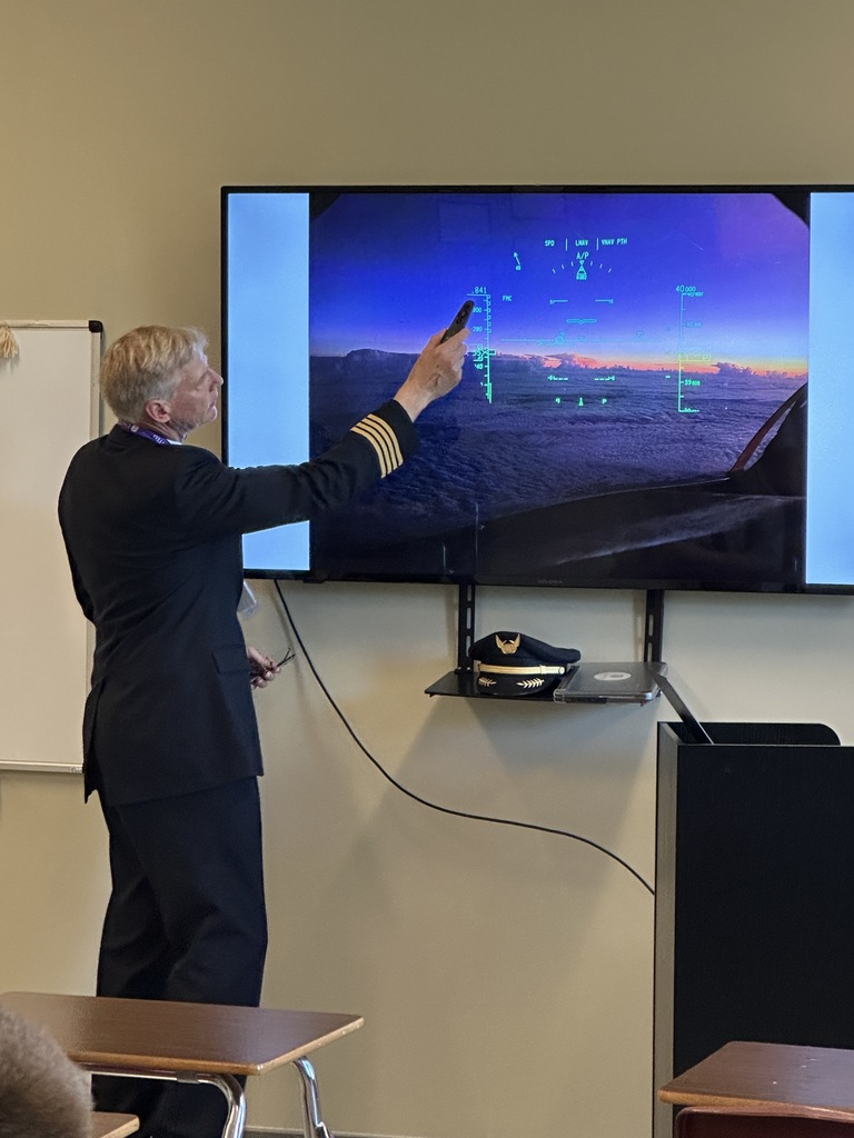 aviation teacher pointing to a picture of the airplane he flew
