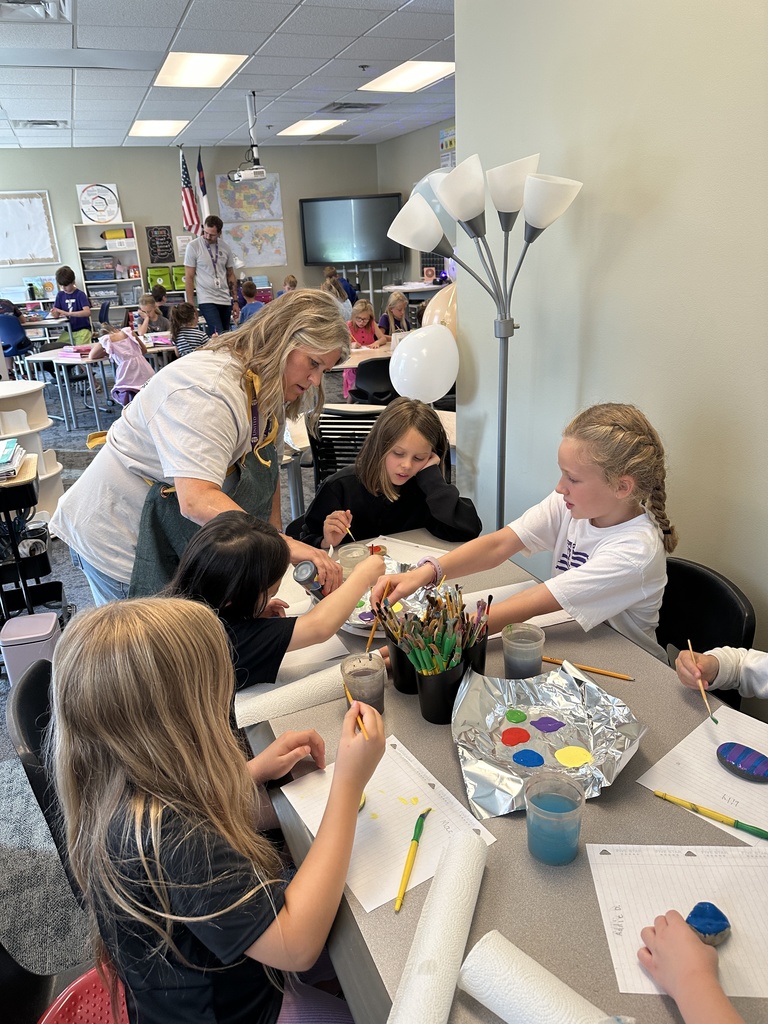 teacher helping students paint rocks