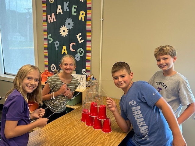 students working in teams to try and stack cups without using their hands