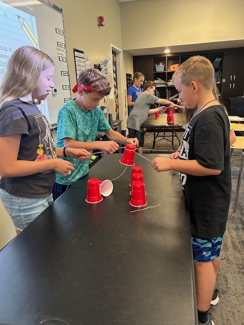 students working in teams to try and stack cups without using their hands
