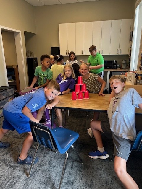students working in teams to try and stack cups without using their hands