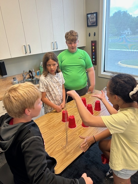 students working in teams to try and stack cups without using their hands