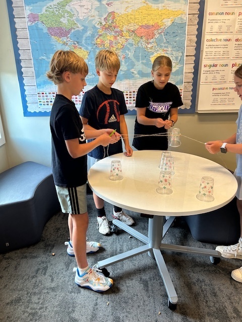 students working in teams to try and stack cups without using their hands