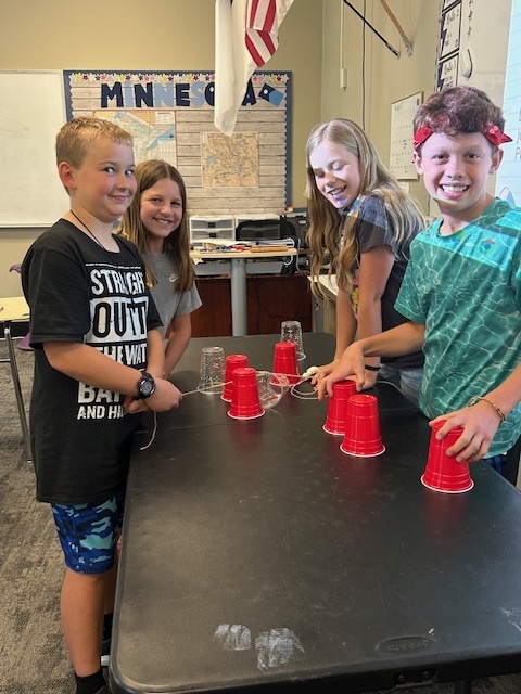 students working in teams to try and stack cups without using their hands
