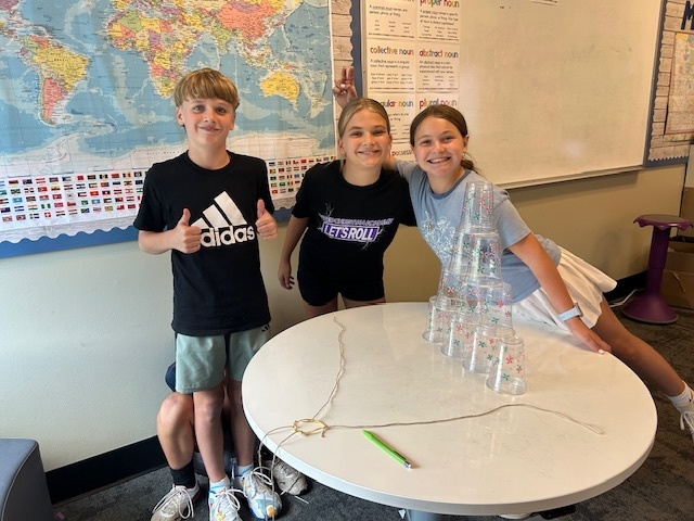 students working in teams to try and stack cups without using their hands
