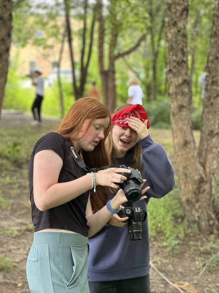 students guiding a blindfolded classmate around so they can take photographs outside