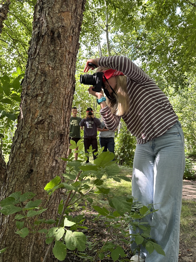 students guiding a blindfolded classmate around so they can take photographs outside